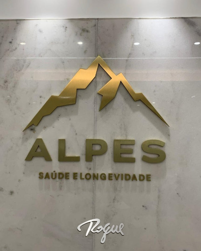 Alpes Saúde e Longevidade: Logomarca em alto relevo de latão dourado com escovado fino.